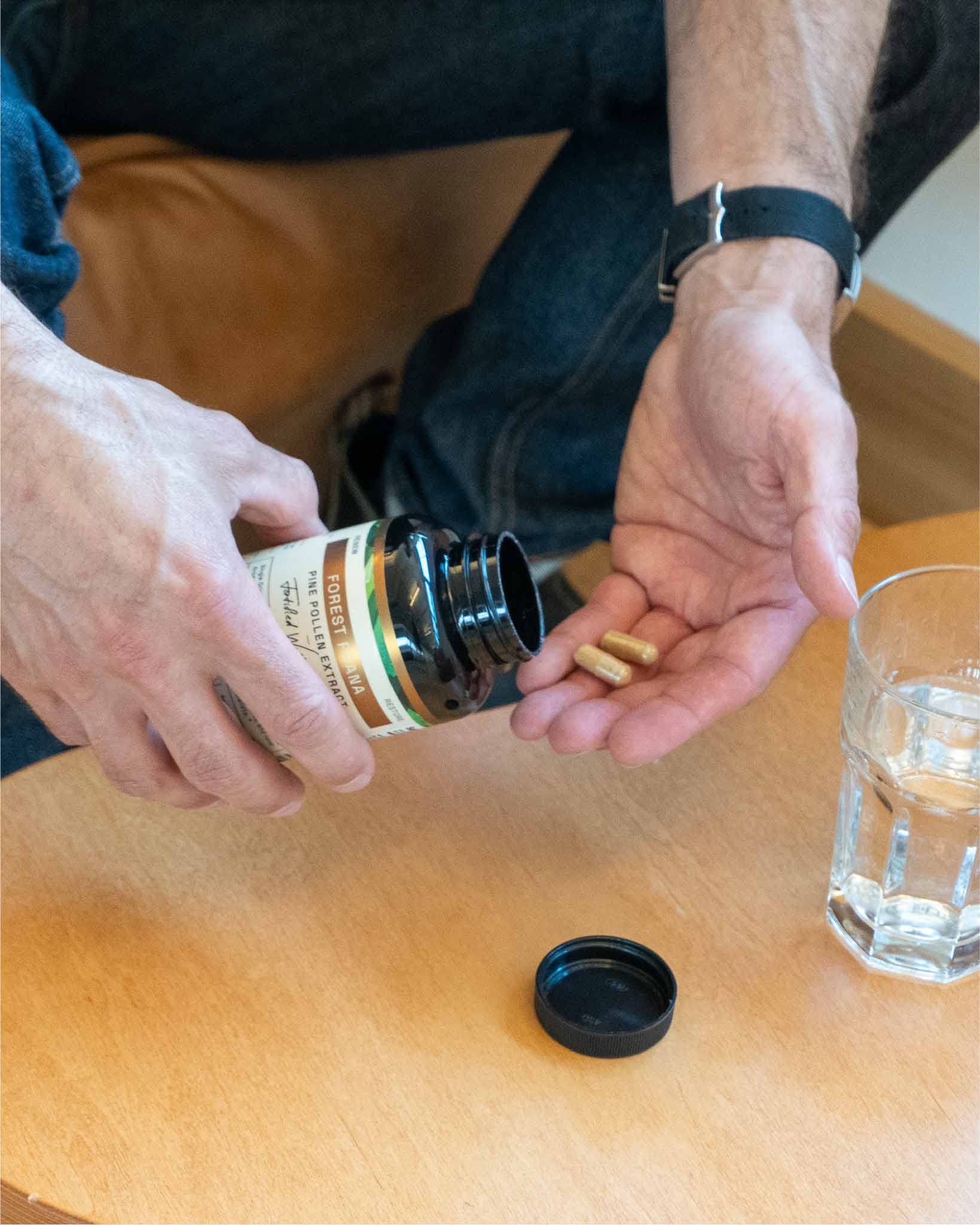 Measuring capsules into hand beside water glass