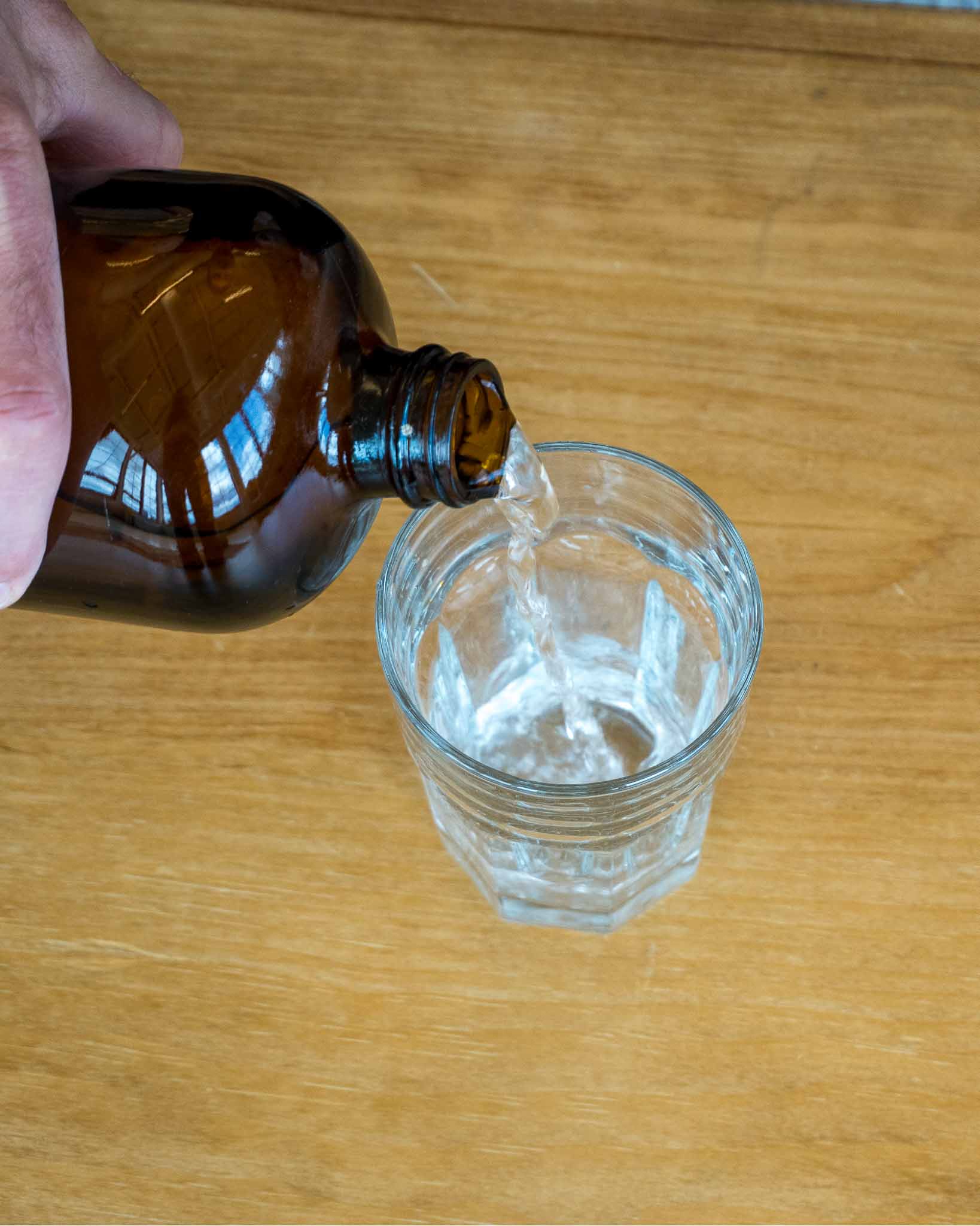 Holding a glass dropper above a tincture bottle to measure a serving